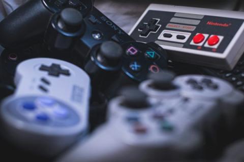 A close-up collection of retro game controllers is shown. Nintendo, Super Nintendo and two different original Playstation controllers