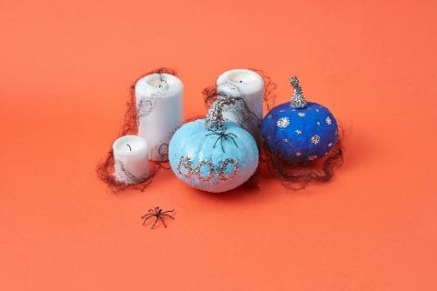 Stock photo of two small painted pumpkins and some candles covered in fake cobwebs