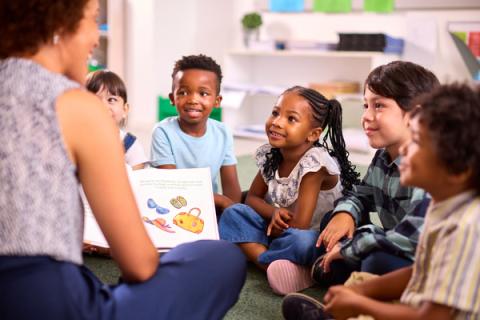 Group of children sit and listen as they are read a story during storytime