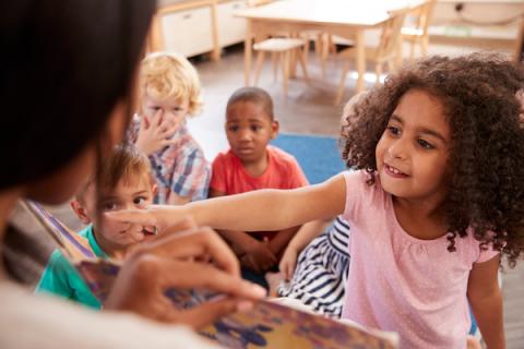 Young girl points to picture in a book during storytime