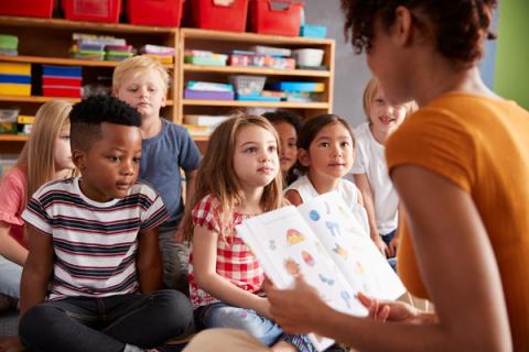 group of children sit and listen while being read a story