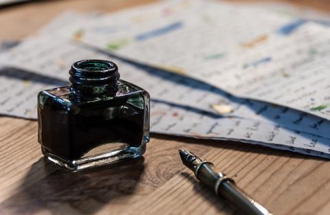 papers with fountain pen and open bottle of ink