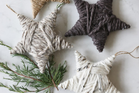 DIY star ornaments in neutral tones made from yarn wrapped around a cardboard or foam star template