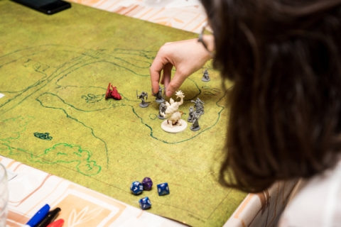 person moving Dungeon and Dragon character pieces on a green map