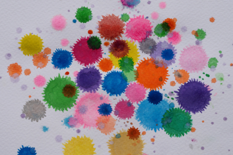 colorful watercolor paint dots in different sizes splatter dropped on white paper 