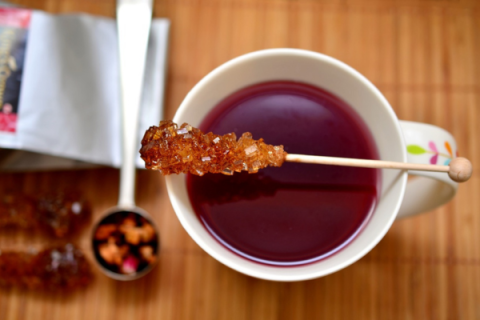 mug of tea with rock sugar stick resting across mug