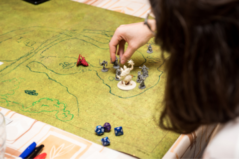 person moving Dungeon and Dragon character pieces on a green map