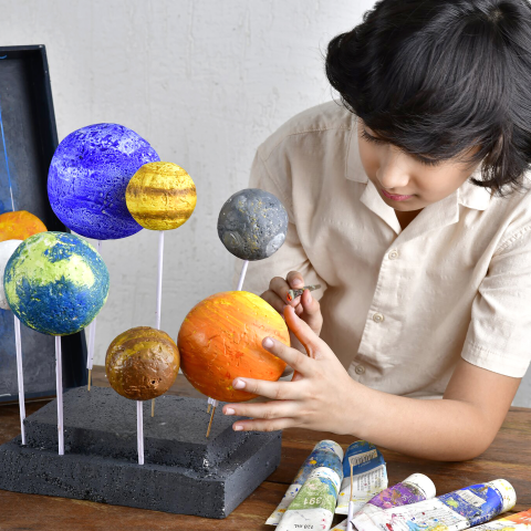 Child painting solar system display.